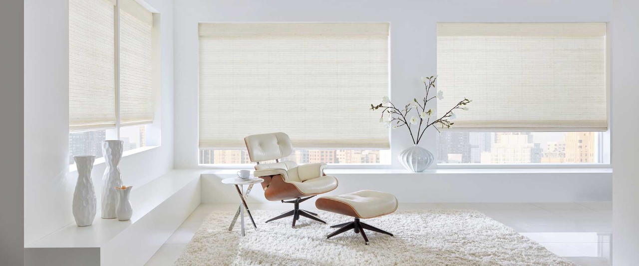 White living room with single chair and woven wooden shades.